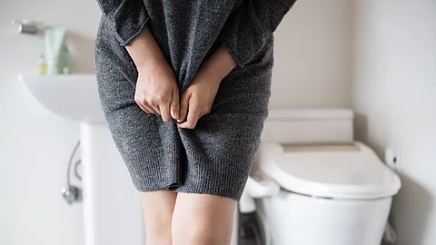 A woman wearing knitwear is complaining of pain from urinary inc