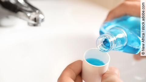 Man pouring mouthwash from bottle into cap in bathroom, closeup.