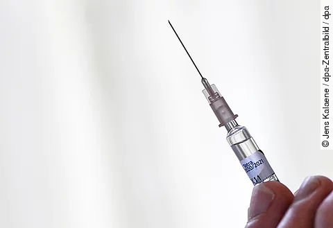 Grippeschutzimpfung - eine Hand hält eine Spritze zur intramuskulären Injektion des Impfstoffs