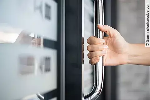 Closeup woman hand holding the door bar to open the door with gl