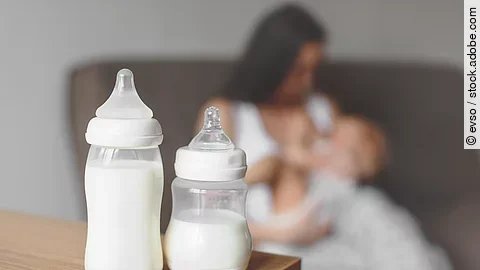 Bottles with breast milk on the background of mother holding in Bottles with breast milk on the background of mother holding in