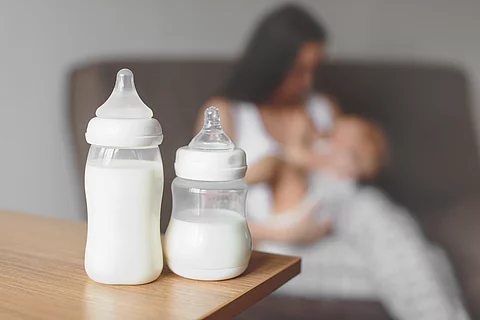 Bottles with breast milk on the background of mother holding in 