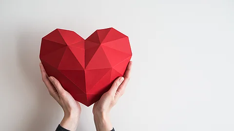 Female hands holding red polygonal heart shape
