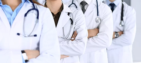 Group of modern doctors standing as a team with arms crossed in