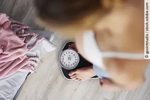 Unrecognizable pregnant woman standing on scale