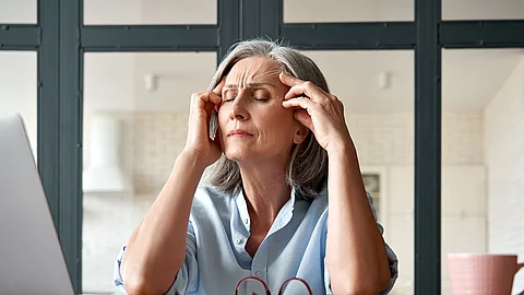 Tired stressed old mature business woman suffering from headache