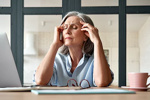 Tired stressed old mature business woman suffering from headache