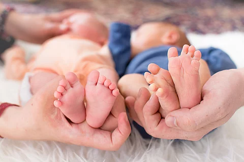 Small feet of newborn premature twins in parent hand and one of Small feet of newborn premature twins in parent hand and one of