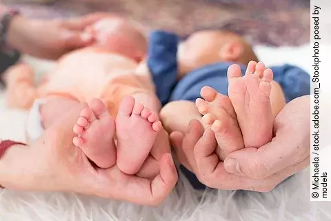 Small feet of newborn premature twins in parent hand and one of 