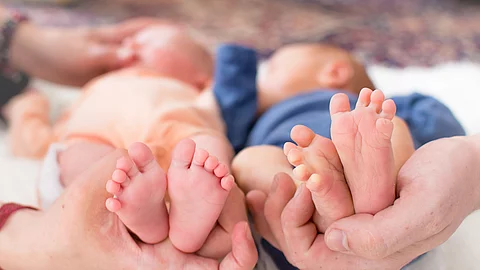 Small feet of newborn premature twins in parent hand and one of 