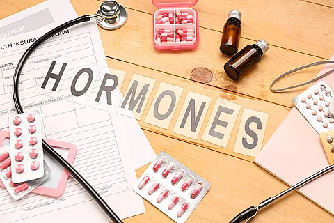 Word HORMONES with pills and medical supplies on wooden background