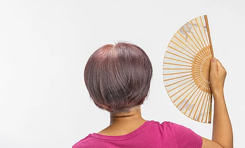 Frau in der Menopause fächert sich Luft zu