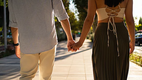 Romantic couple holding hands enjoying a walk on a sunny street Pärchen hält Händchen beim Spazierengehen