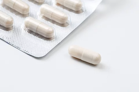 Pile of white capsules probiotic powder inside. Copy space. High