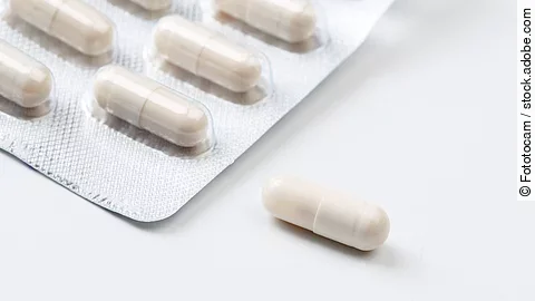 Pile of white capsules probiotic powder inside. Copy space. High