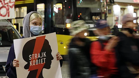 Vermummte Frau hält Protestschild hoch