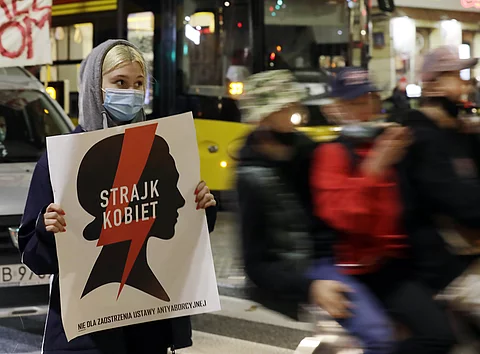Vermummte Frau hält Protestschild hoch