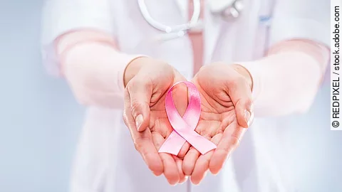 pink ribbon in the hands of a doctor, symbol for breastcancer