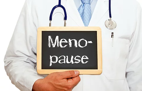 Arzt hält Schild mit Beschriftung "Menopause" hoch