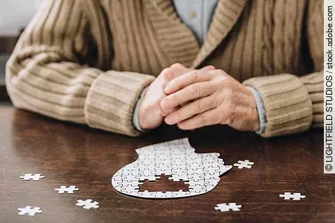 cropped view of senior man playing with puzzles on table
