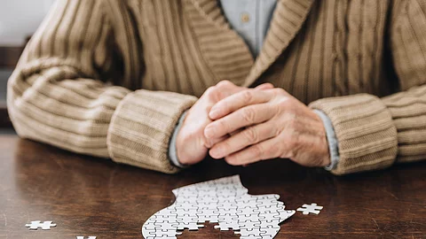 cropped view of senior man playing with puzzles on table