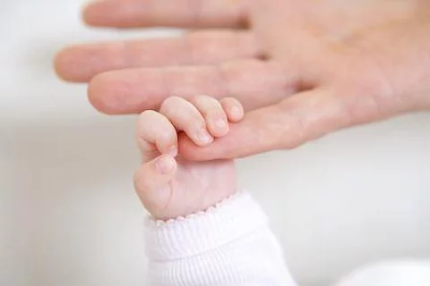 Hand eines Babys ergreift Finger seines Elternteils