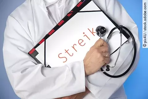 Arzt hält Streikschild vor der Brust